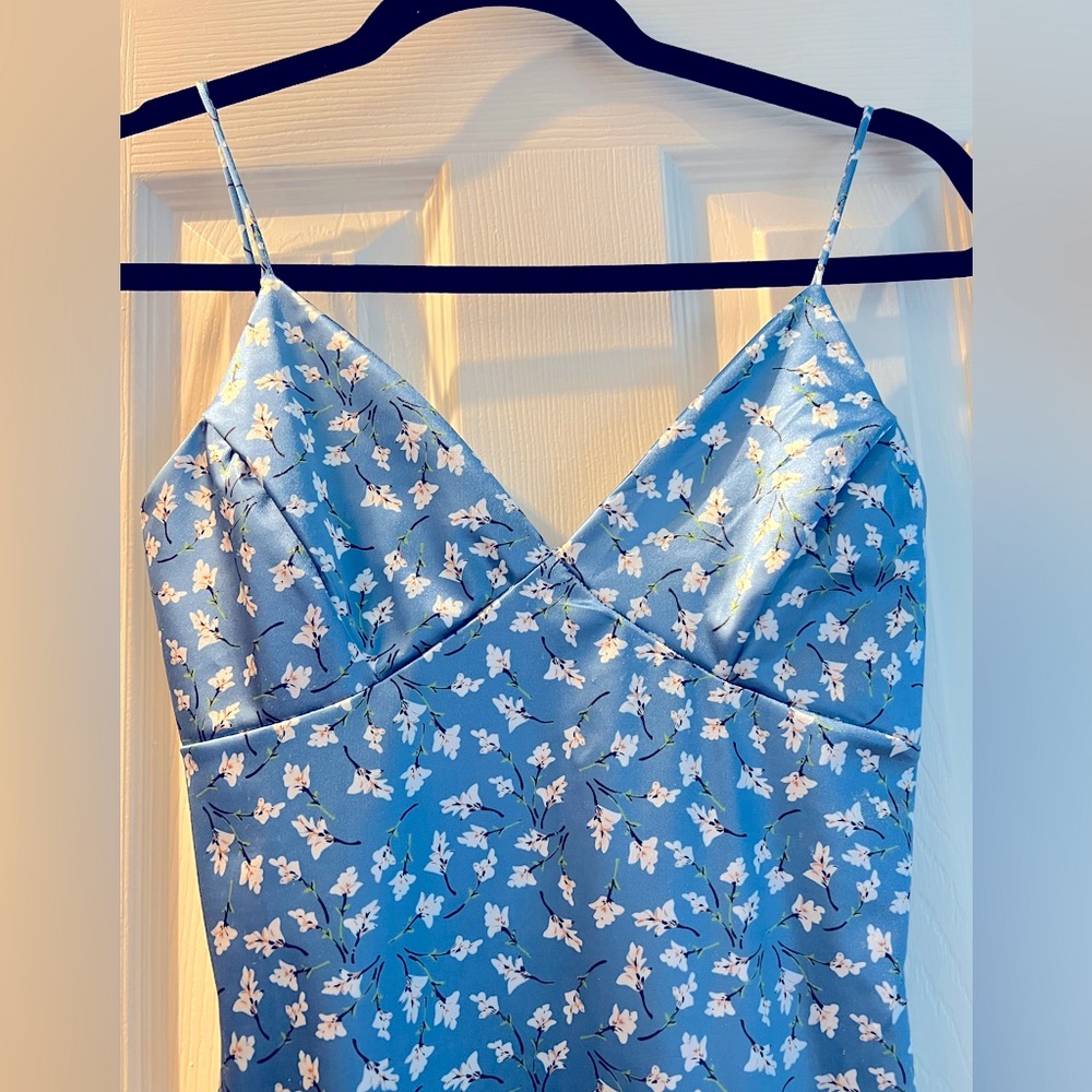 A small size blue color dress has white flowers. Thick Satin fabric.